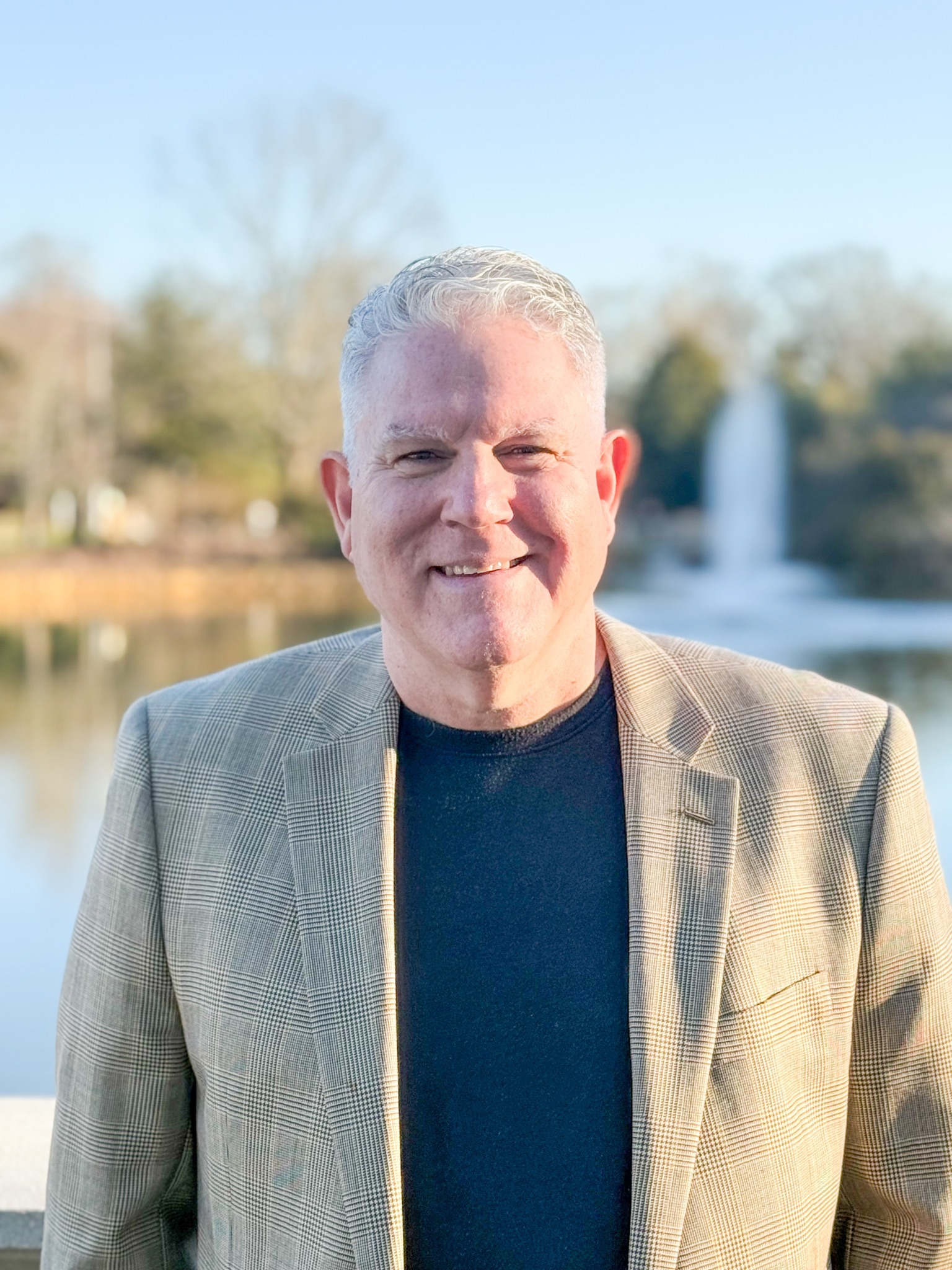 Paul Higginbotham, coach and consultant, smiling outdoors by a lake